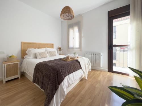 a white bedroom with a large bed with a wooden floor at Apartamentos Turísticos Con Alma in Plasencia