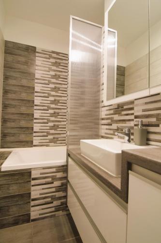 a bathroom with a sink and a tub and a mirror at Tisza River Apartman in Szeged