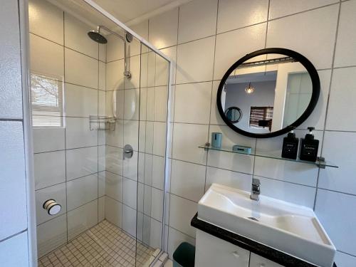 a bathroom with a shower and a sink and a mirror at Private Cottage on Alamein in Cape Town