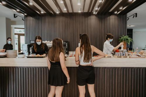 two women wearing face masks standing at a counter in a restaurant at Tenuta Terre di Bosco Oasi di Relax nel Cilento in San Giovanni a Piro
