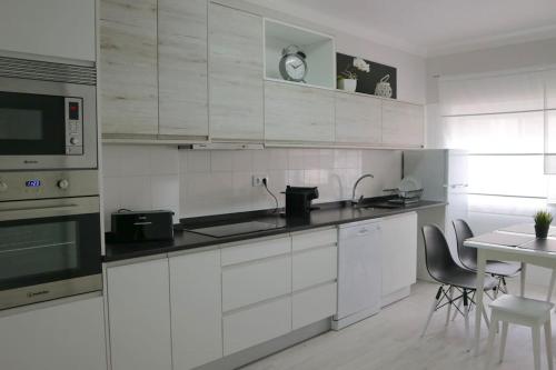 a kitchen with white cabinets and a table with chairs at Beautiful and cozy flat close to beach and center in Lagos