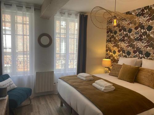 une chambre avec un grand lit avec des serviettes dessus dans l'établissement Le Duplex d'Au Sans Pareil -, à Honfleur