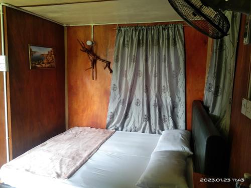 a bed in a room with a window with a white sheet at Tammoyo Place in Kudat