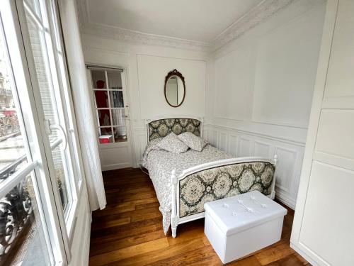 een kleine witte slaapkamer met een bed en een spiegel bij Van Gogh's Apartment - Montmartre in Parijs