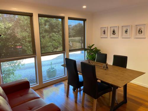 a dining room with a table and chairs and windows at The Delightful Tee House - Kilmore in Kilmore