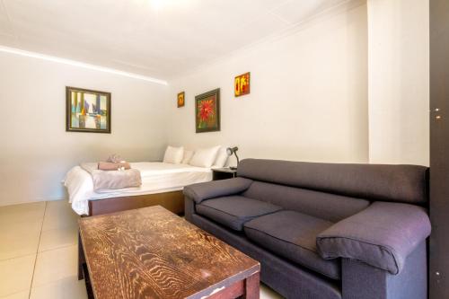 a living room with a couch and a bed at Linden Guest House in Johannesburg