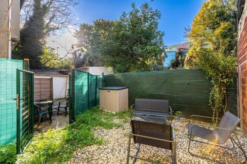 a backyard with a fence and a grill and chairs at Cénoslocs Bondy - Paris à vos pieds pour 4 personnes avec Jardin & Wifi in Bondy