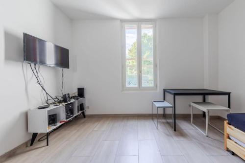 a living room with a black table and a television at Cénoslocs Bondy - Paris à vos pieds pour 4 personnes avec Jardin & Wifi in Bondy