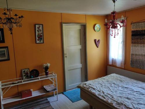 una camera da letto con pareti arancioni, un letto e una finestra di Hideaway for holiday season, House with two saunas a Hämeenlinna