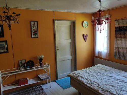 a bedroom with orange walls and a bed and a window at Hideaway for holiday season, hot tube, two saunas in Hämeenlinna