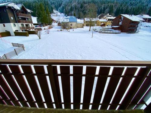 uma vista para um pátio coberto de neve a partir de uma varanda em Charmant appartement au pied des pistes de Lelex em Lélex