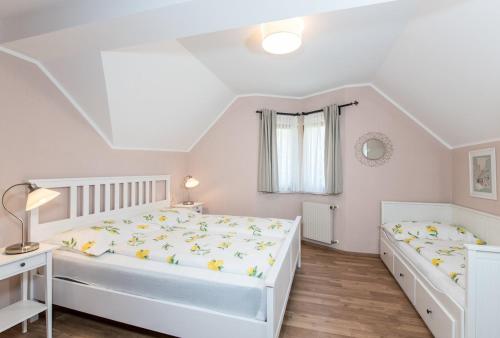 a white bedroom with two beds and a desk at Appartements Allmaier in Pörtschach am Wörthersee