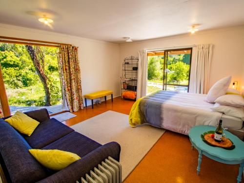 um quarto com uma cama, um sofá e uma janela em Bay Cottage - Takaka Holiday Unit em Takaka