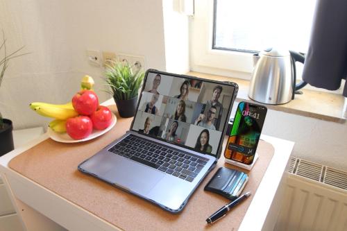 a laptop computer sitting on a desk with a cell phone at Downtown Apartments Ulm - im Herzen von Ulm & komfortable Boxspringbetten in Ulm