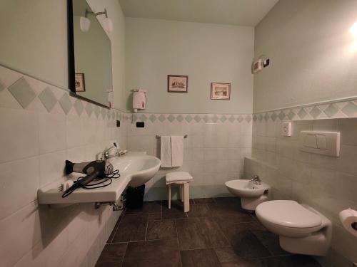 a white bathroom with a sink and a toilet at All'Imperatore in Cherasco