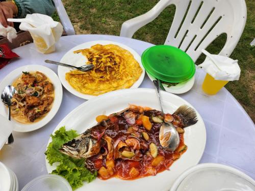 a white table with plates of food on it at AqeelAelisya Chalet Malacca beach in Kampong Bukit Darat