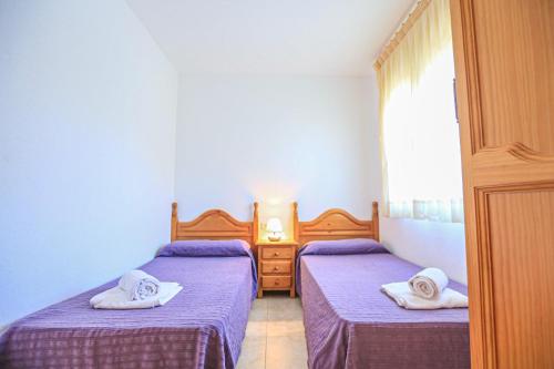 two beds in a room with purple sheets and towels at Sol Millet Litoral - ONLY FAMILIES in Cambrils