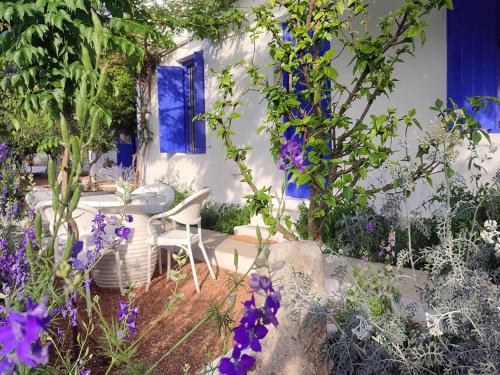 een tuin met paarse bloemen en een tafel en stoelen bij Anticlea II in Vathi