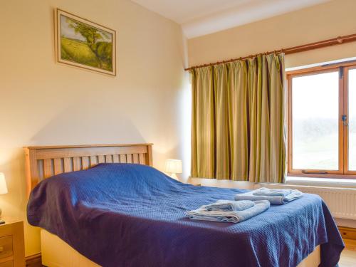 a bedroom with a bed with blue sheets and a window at Kingfisher - Uk42520 in Aldwincle Saint Peter