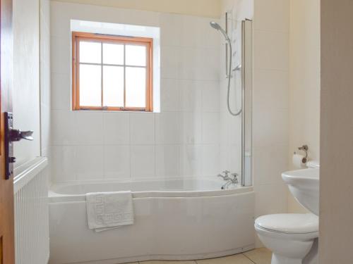 a white bathroom with a tub and a toilet at Kingfisher - Uk42520 in Aldwincle Saint Peter