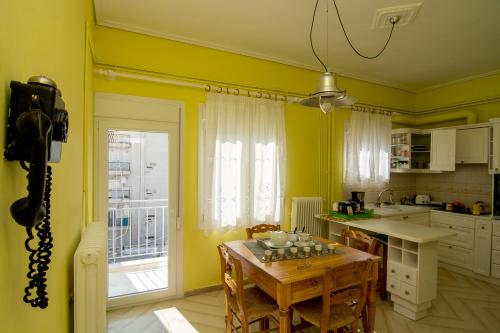 une cuisine avec des murs jaunes, une table et des chaises dans l'établissement Areti' s Home, à Vólos