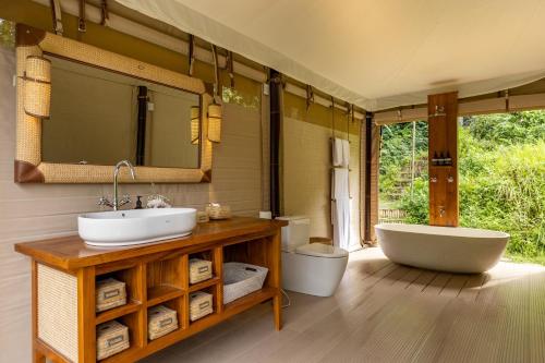 a bathroom with two sinks and a tub and a mirror at Nadi Nature Resort - Adults Only in Tabanan