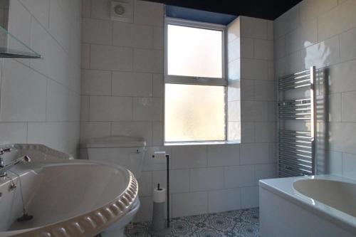La salle de bains est pourvue d'une baignoire, de toilettes et d'une fenêtre. dans l'établissement Lovely 4 Bed House in Huddersfield with parking, à Huddersfield