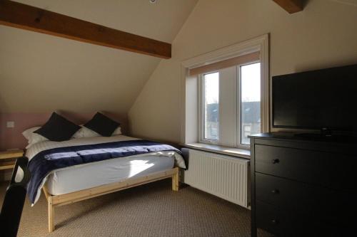 a bedroom with a bed and a window and a television at Lovely 4 Bed House in Huddersfield with parking in Huddersfield