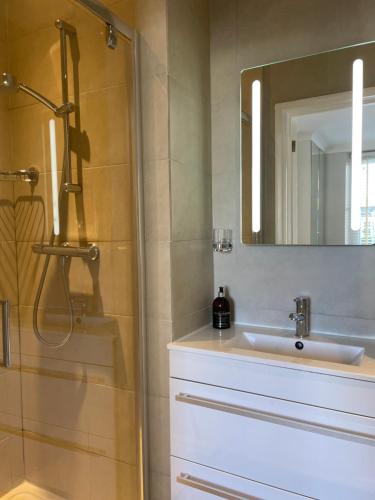 y baño con lavabo y ducha con espejo. en Wren House, en Sidmouth