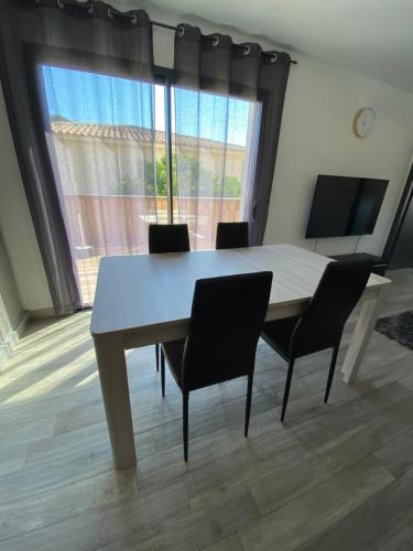 een eettafel met stoelen en een groot raam bij Maison récente de 50 m2 pour 4 personnes in Porto-Vecchio