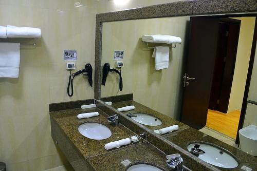 un baño con 3 lavabos en una habitación de hotel en Palm Inn Hotel Doha en Doha