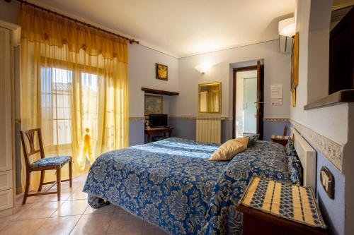 a bedroom with a bed and a chair and a window at B&B Il Tufo Rosa in Pitigliano