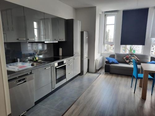 eine Küche mit Küchengeräten aus Edelstahl und ein Wohnzimmer in der Unterkunft Gästewohnung Alt Salbke mit Küche in Magdeburg