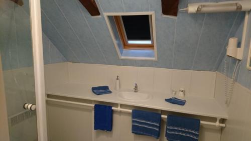a bathroom with a sink and a mirror and blue towels at Chambres d'Hôtes Le Pont in Égletons