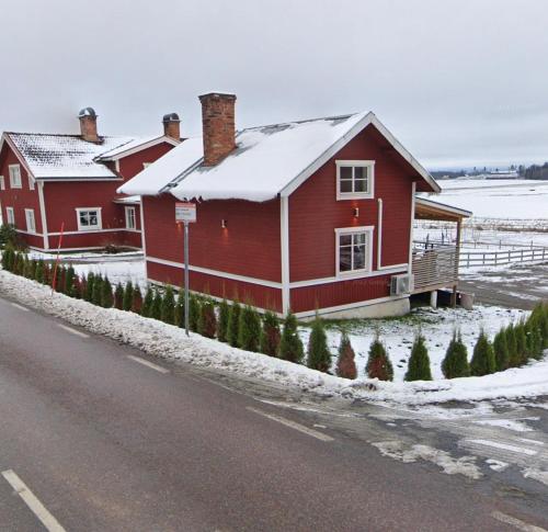 a red house on the side of a road with snow at Backes Lillstuga in Borlänge