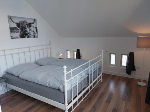 a bedroom with a white bed with a cow on the wall at Stadthaus mit Dachterrasse in Varel