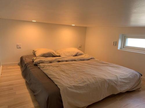 a large bed in a bedroom with a window at Your own 30sqm house with kitchen, sauna and loft. in Malmö
