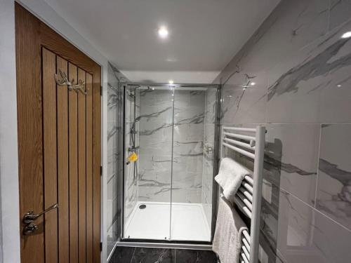 a bathroom with a shower with a glass door at Cosy Alpine Cottage in the heart of Lancashire in Catterall