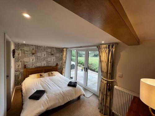 a bedroom with a bed and a large window at Cosy Alpine Cottage in the heart of Lancashire in Catterall