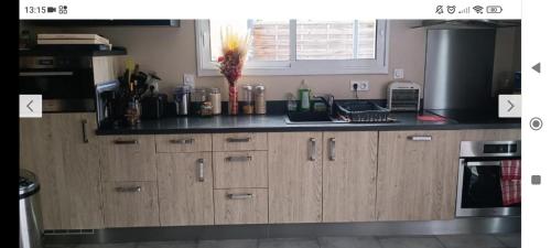 une cuisine avec des armoires en bois et un comptoir noir dans l'établissement Maison pour location de chambre circuit 24H et GP, à Aigné