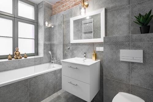 La salle de bains est pourvue d'un lavabo, d'une baignoire et de toilettes. dans l'établissement Apartamenty K&B Toruń, à Toruń