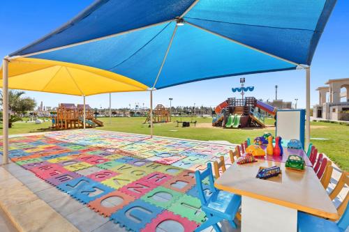 a table with a blue umbrella and a playground at Pickalbatros Aqua Park Sharm El Sheikh in Sharm El Sheikh
