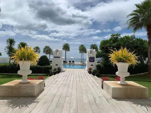 a walkway with two white vases with plants in them at Seaview Studio with beach access Hua Hin KhaoTao in Ban Bo Kaeo