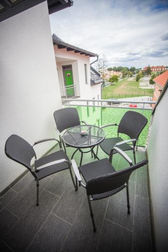 balcón con 4 sillas, mesa y vistas en Azúr Ház Gyöngyvirág Apartman en Sárvár