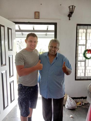 two men giving thumbs up in a living room at The Misty Mountain Guest House in Haldummulla