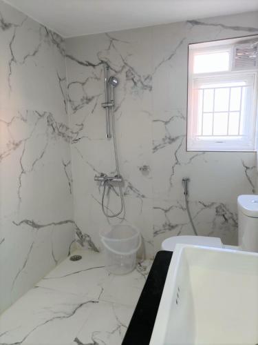 a bathroom with white marble walls and a shower at Two Seas Residence in Ooty