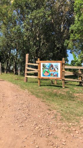 a sign on a fence next to a dirt road at Chalé Envidraçado Recanto Verde dos Canyons in Praia Grande