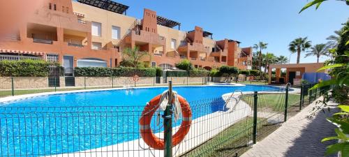 une piscine en face d'un bâtiment dans l'établissement Homes of Spain, Apartamentos Paraiso de Vera Playa, Ed Tahiti bajo H, a pie de la playa, vistas piscina, à Vera