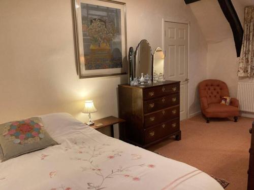 a bedroom with a bed and a dresser and a chair at Little Reeds in Bovey Tracey