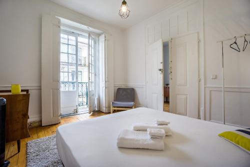 a white bedroom with two towels on a bed at Original Lisbon Guesthouse in Lisbon